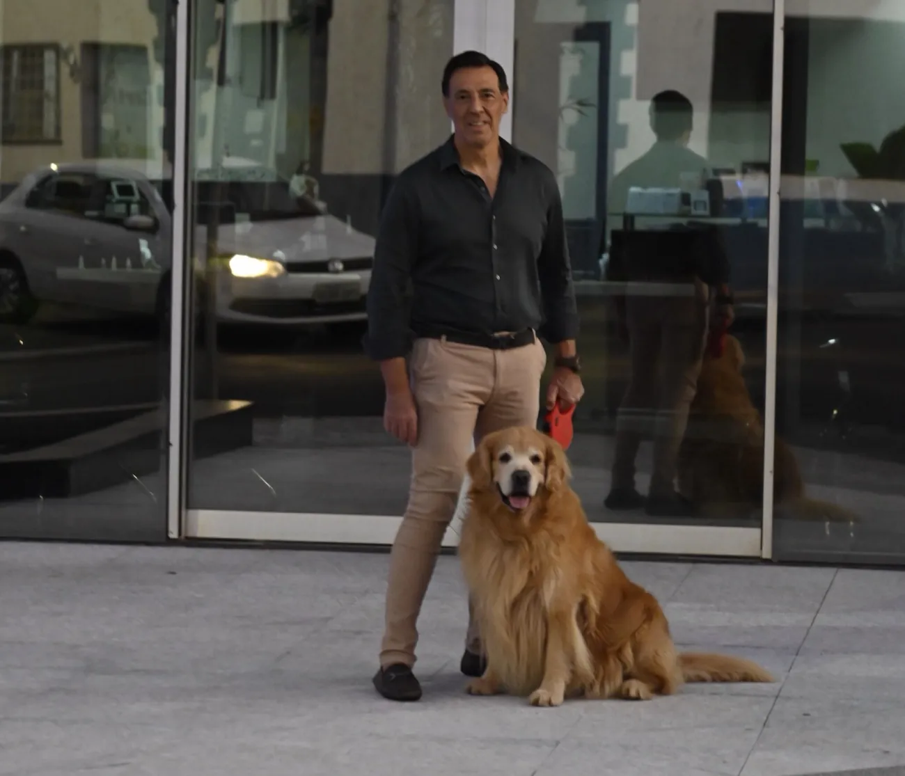 Dr. Celso Davi Lopes na entrada do Hospital da Visão de Bebedouro, ao lado de seu cão golden retriever